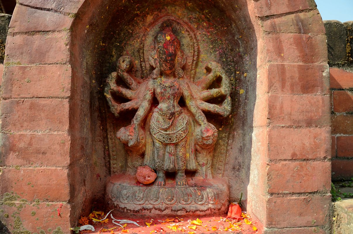 Kathmandu Changu Narayan 35 Figure With Eight Arms That I Think Is Durga Is On East Side Of Parijat Tree Platform On North East Side Of Changu Narayan A rough statue of a figure with eighth arms that I think is Durga is on the east side of the parijat tree platform in the north east area of Changu Narayan. It is hard to make out what the arms are holding.